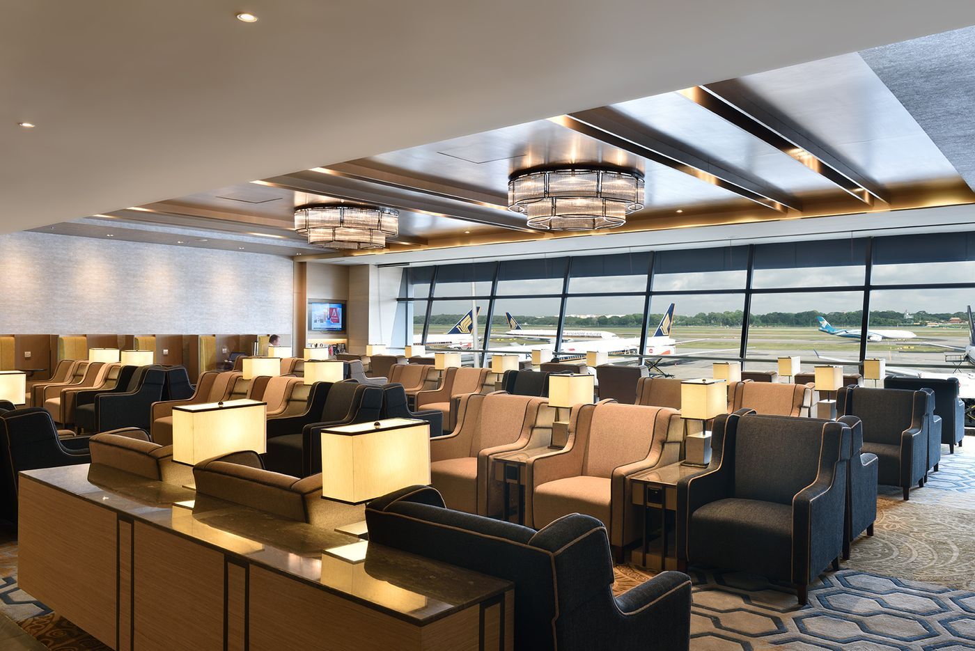 A spacious airport business lounge with rows of lounge chairs and a view of the tarmac.